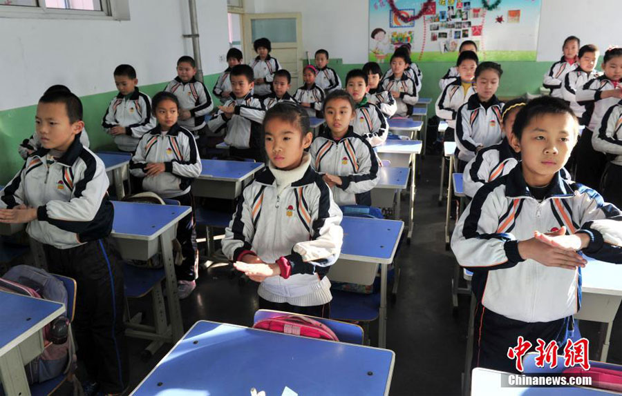 12月11日,河北石家庄光明路小学,全校的孩子都在教室练习一套“防霾”武术健身操。图为孩子在教室认真地“练功”。中新社发 翟羽佳 摄
