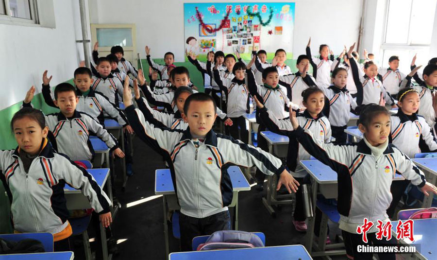 12月11日,河北石家庄光明路小学,全校的孩子都在教室练习一套“防霾”武术健身操。图为孩子在教室认真地“练功”。中新社发 翟羽佳 摄
