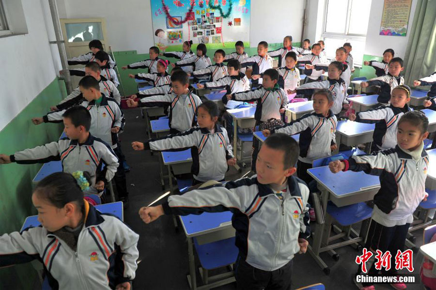 12月11日,河北石家庄光明路小学,全校的孩子都在教室练习一套“防霾”武术健身操。图为孩子在教室认真地“练功”。中新社发 翟羽佳 摄