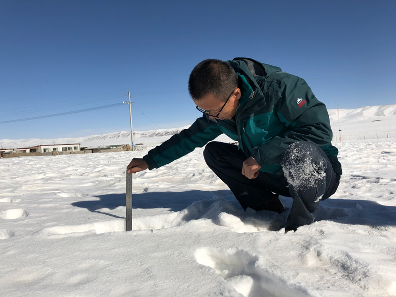 青海省玉樹州氣象局工作人員在雪地中測量積雪厚度